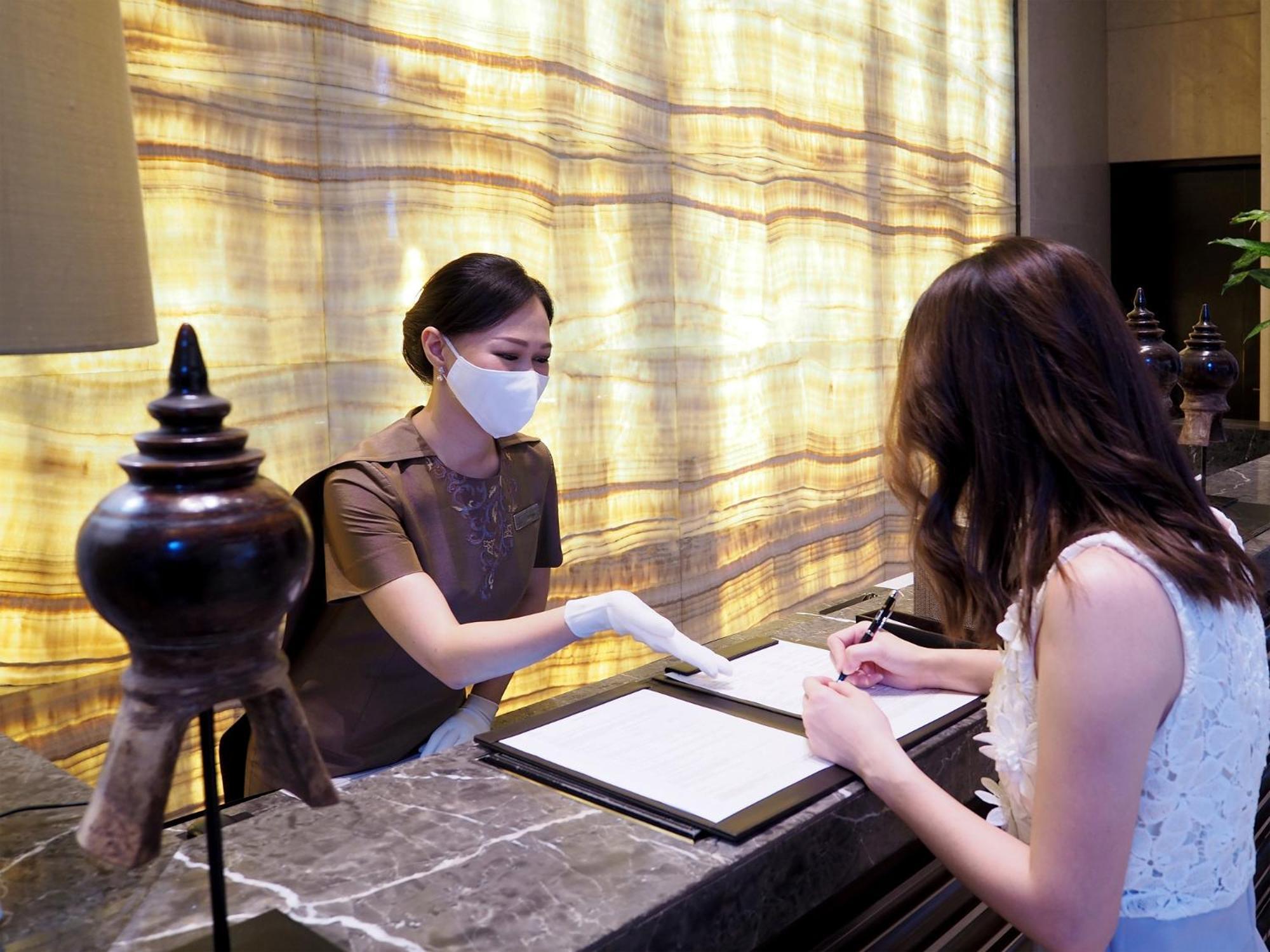 Siam Kempinski Hotel Bangkok Exterior photo A hotel receptionist wearing a face mask